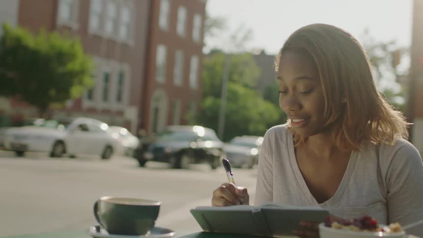 A woman smiles and writes in a notebook