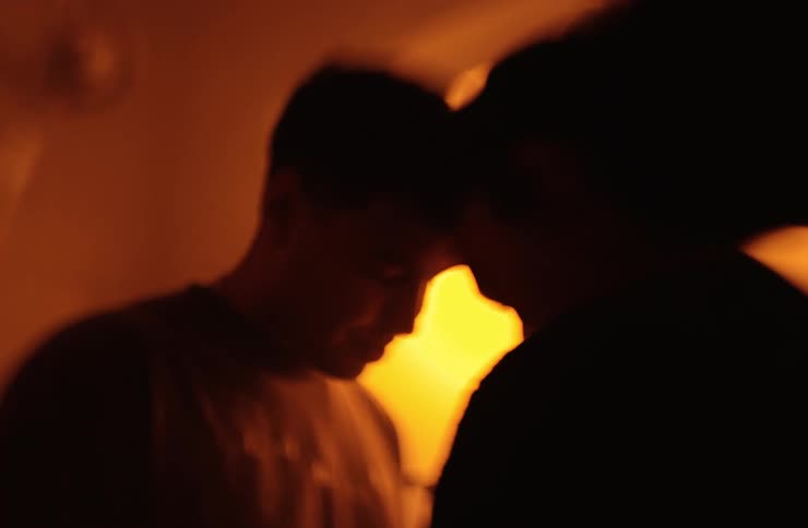 A man and woman romantically slow dancing with their foreheads touching standing in a room with warm lighting