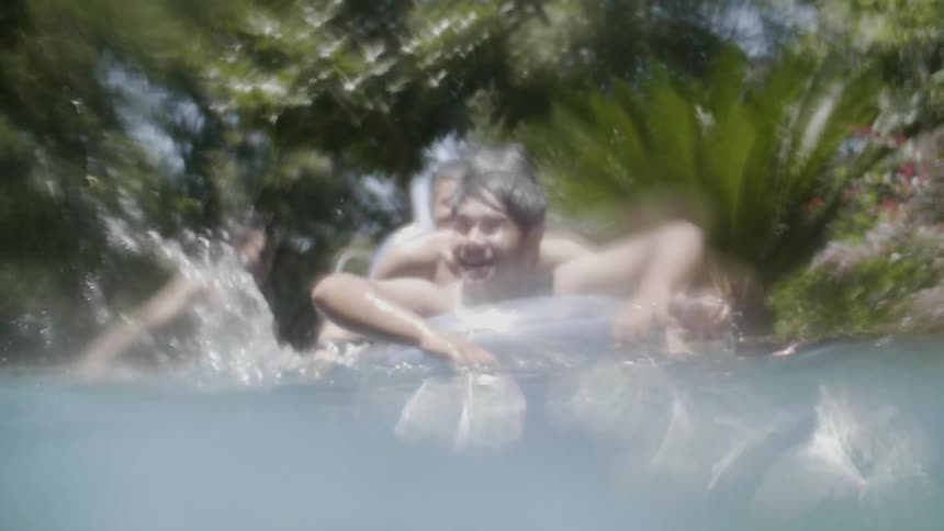 Boys splash and play in an outdoor swimming pool