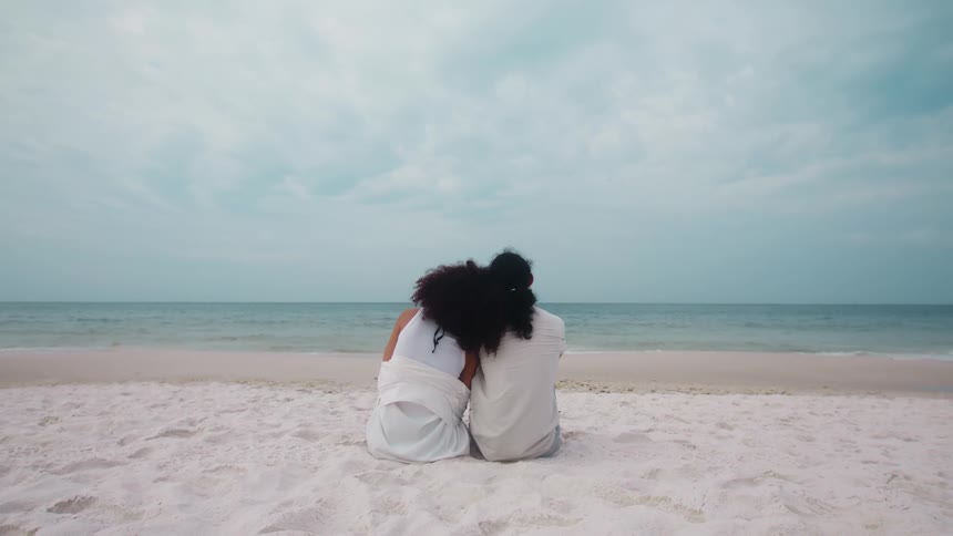 Couple sitting on the sand at the beach together