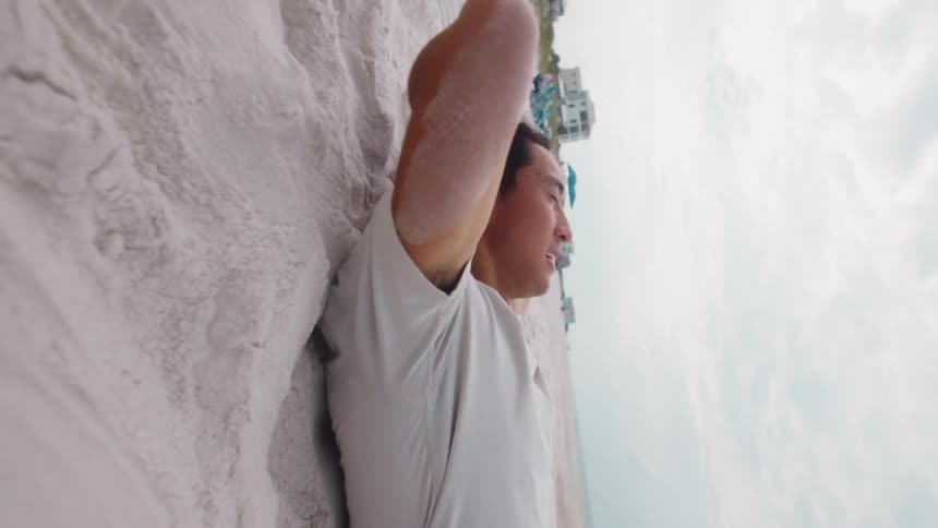 A man relaxes on a sandy beach with his arms behind his head