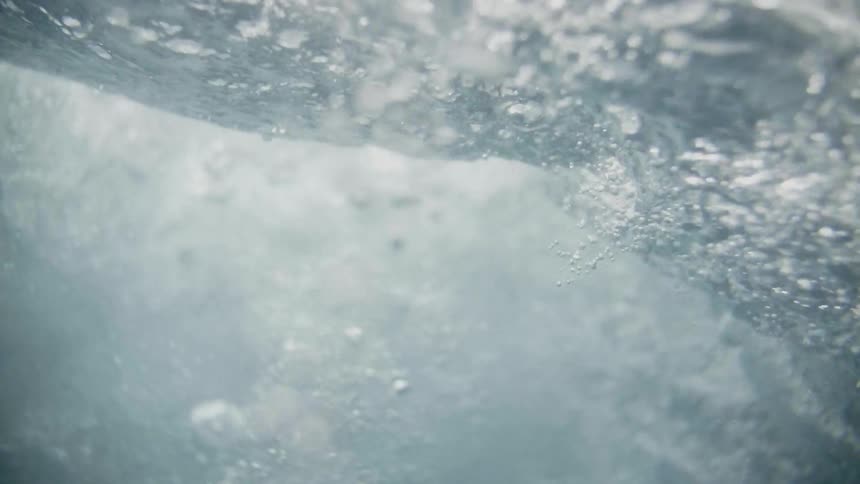 A person jumps into a body of water and bubbles float towards the surface