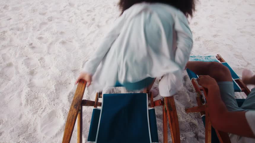 A couple sitting side by side on beach chairs suddenly stood up and ran after each other on the beach sand at midday