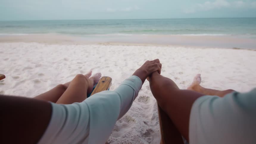 Couple holding hands while relaxing on a beach vacation