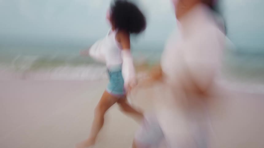 Man and woman holding hands running on the beach