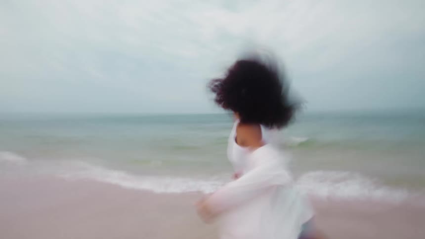 Couple holding hands running along the beach