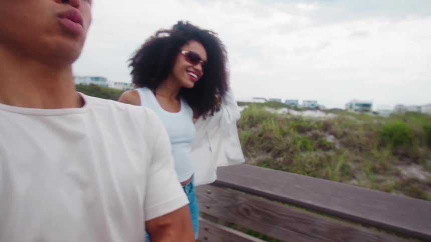 Man and a woman both smiling walking in a beach setting