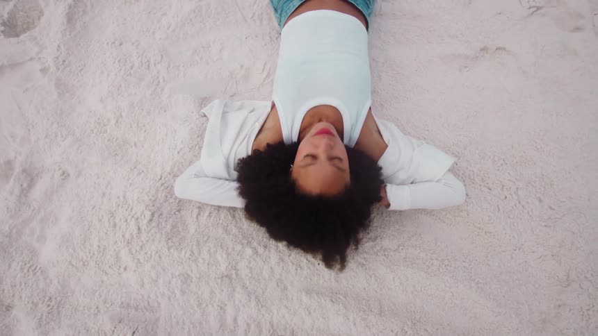 A woman relaxes on white sand