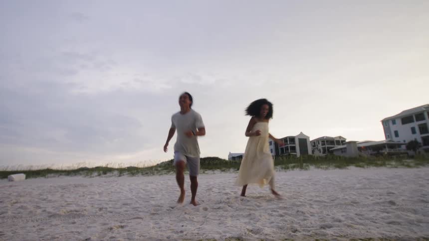 A joyful couple runs playfully on the beach