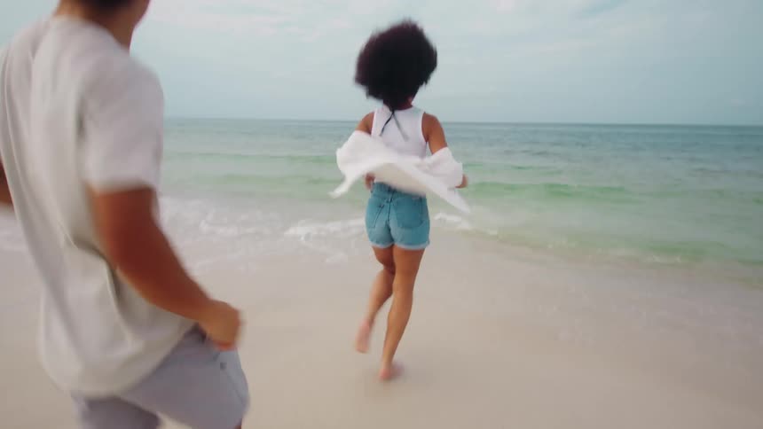 Woman and a man getting up from their chairs and running towards the sea on the beach