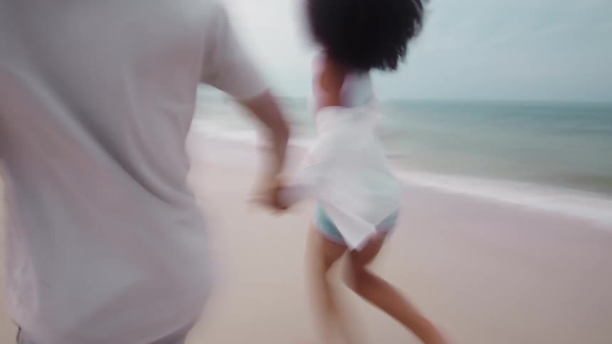 Couple running hand in hand by the sea