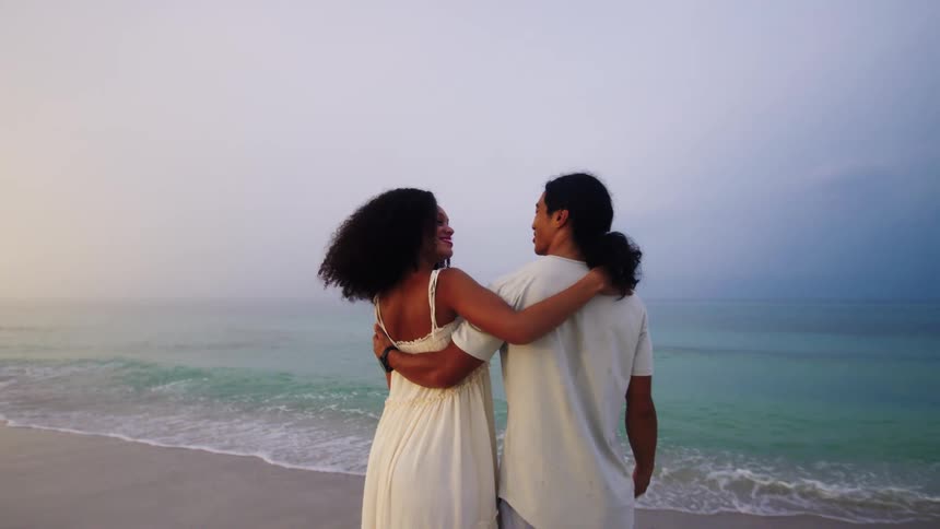 Couple in white clothes hugging on the beach