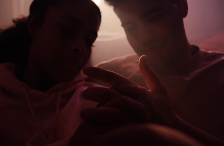 Couple shares a tender moment while holding hands in dim lighting