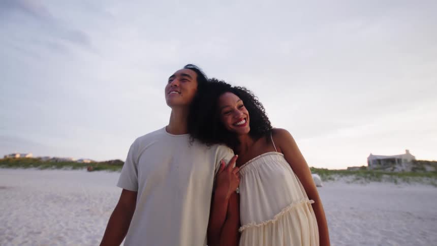 Man and a woman running together on the beach and hugging each other affectionately