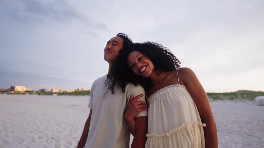 A couple hold each other while walking past the water