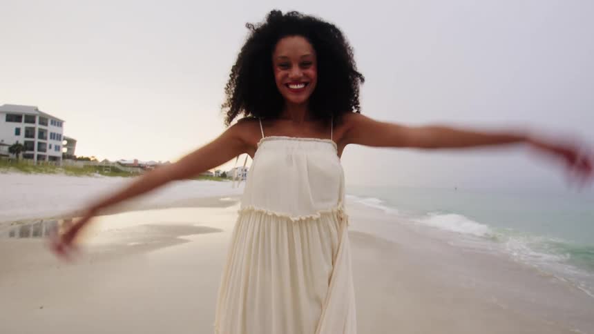 A smiling woman poses for pictures on a beach during vacation