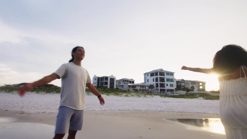 A joyful couple dances and plays together on the beach at sunset