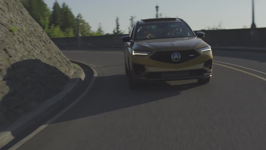 A gold car driving on a freeway with two people seated in the front seats at midday