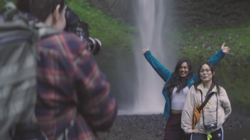 Woman photographing two friends at a waterfall