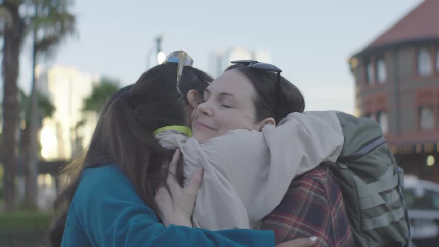 Three friends warmly hug during a joyful reunion outdoors