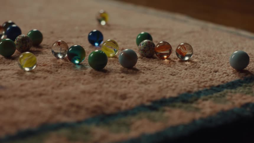 A series of marbles poured onto a rug indoors scattering around