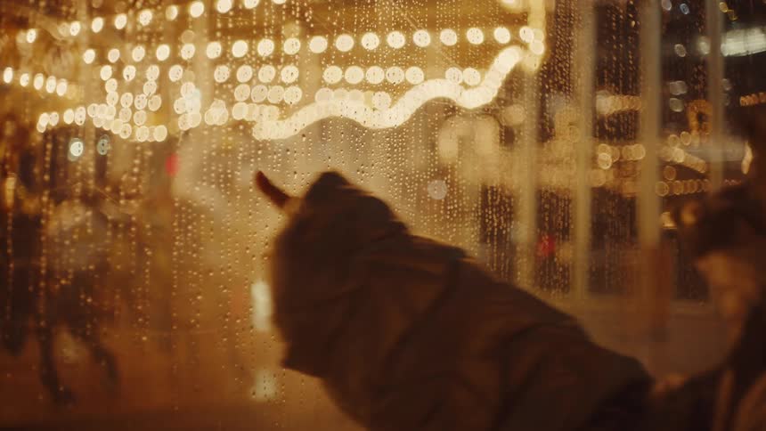 Person blowing and fogging the glass and drawing on it at night