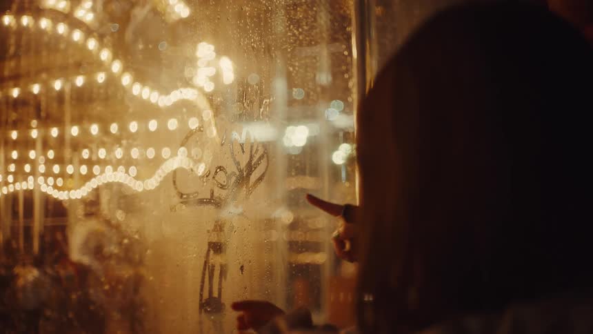 Woman and a child drawing on a foggy glass