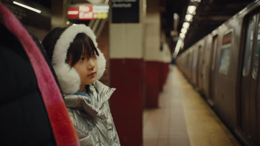 Young girl waits quietly on a subway platform