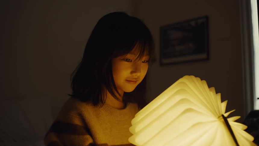Girl opening a book that turns into a lamp