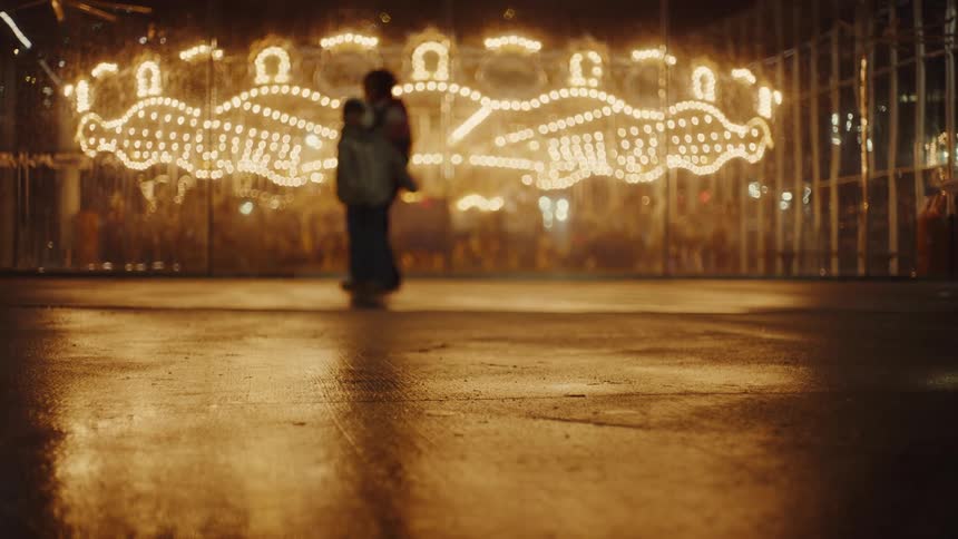 Silhouette of two people playing outside an amusement park at night