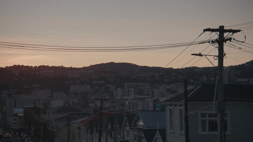A residential neighborhood at sunrise with utility poles lining the street