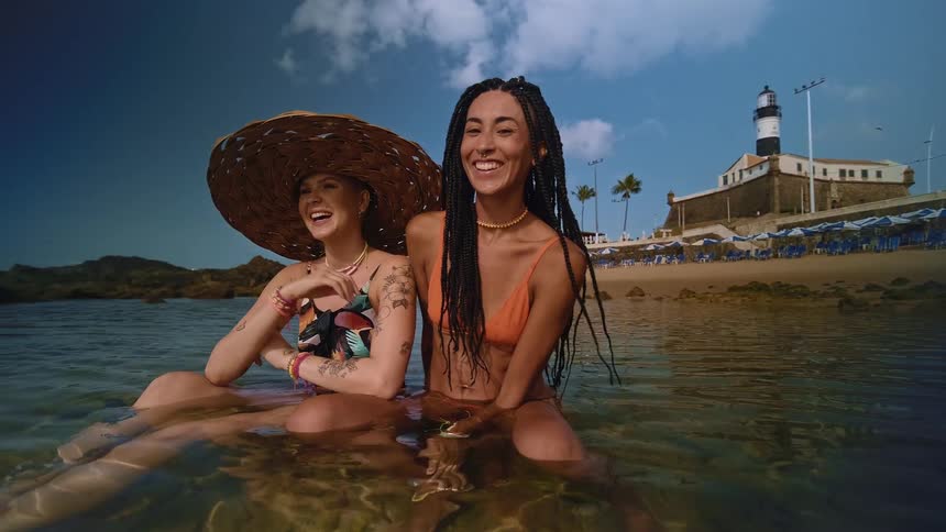Two women sitting in the sea at the beach happy and smiling brightly