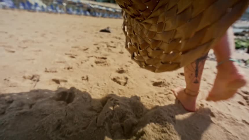 Legs of a person walking barefoot on the sand at the beach
