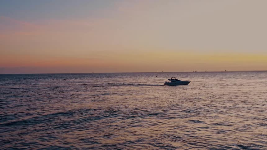 A boat sailing on the ocean at sundown