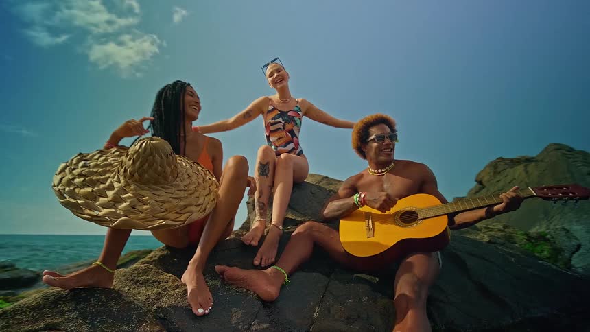 The people sit on the rocks playing guitar and dancing