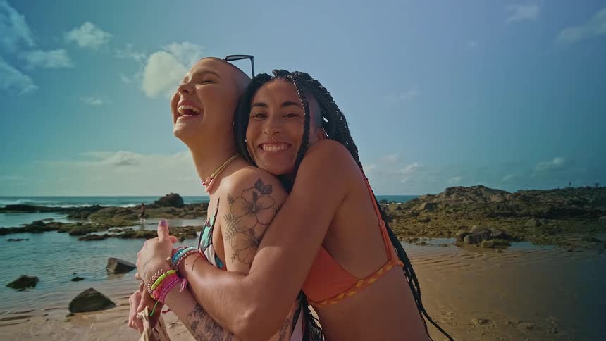 Portrait of two young women hugging each other while playing outdoors at the beach during daytime