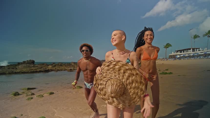 A man and two women running smiling and happy along the shoreline
