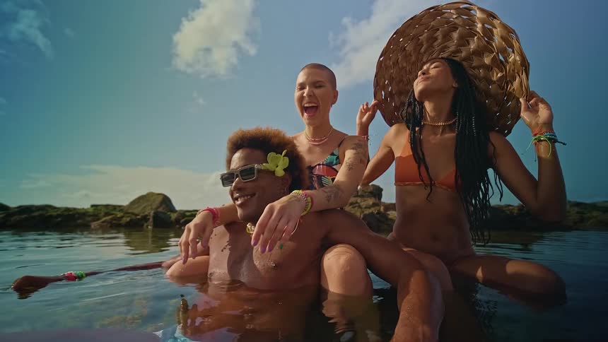 Two women in bikinis and a man enjoying a moment on a calm beach