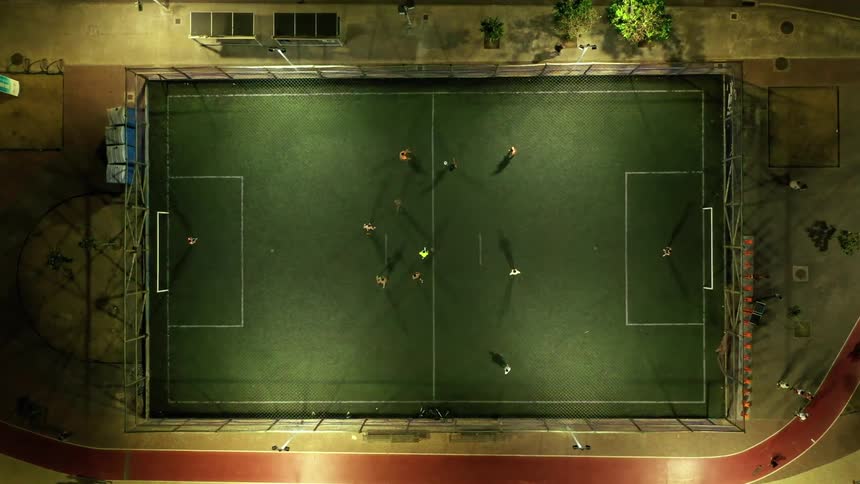A group of people playing soccer on a soccer field at night