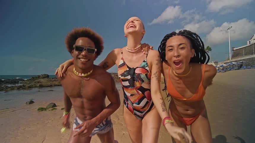 One man and two women running happily and having fun together on the beach