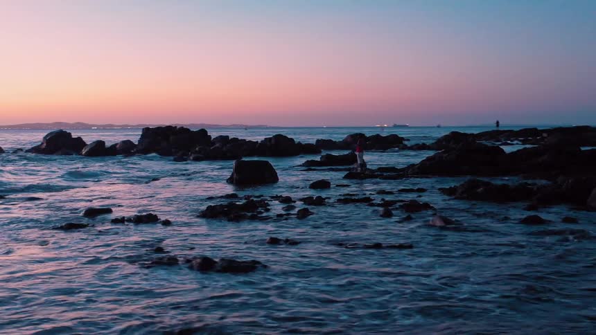 Isolated person on a beach at dawn with a reddish sky