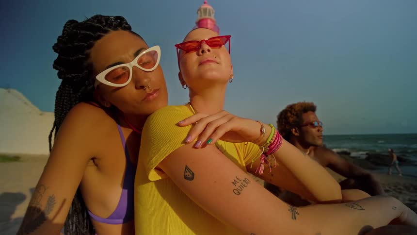 Two women and a man next to them sitting in a beach setting