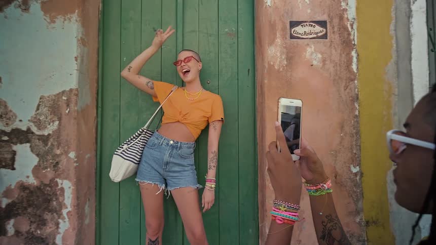 Woman taking a picture of her friend at an old wooden door