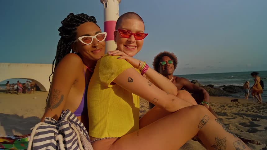 Women sit close together on the sand of the beach