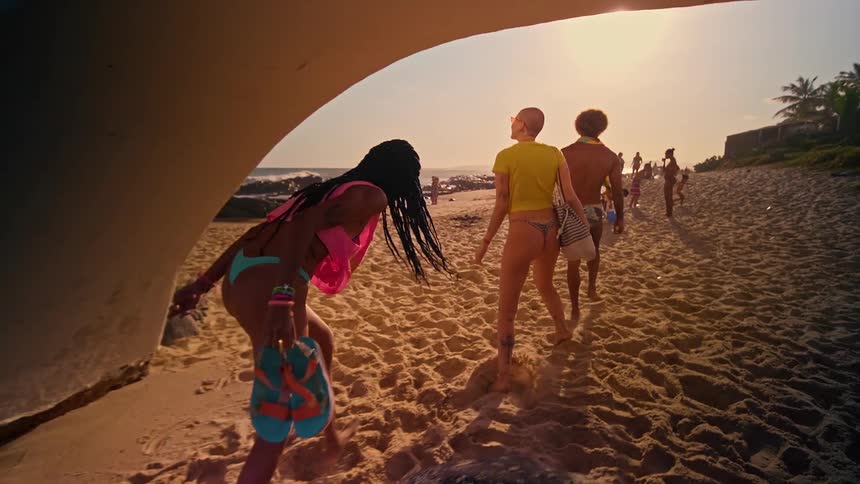 People walking on the beach sand passing through an arch