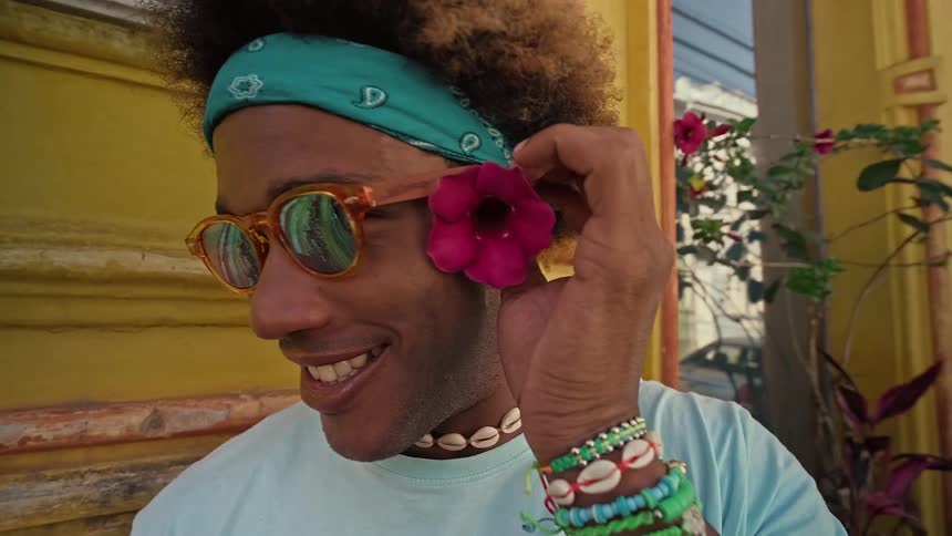 Man in sunglasses putting a rose flower in his ear