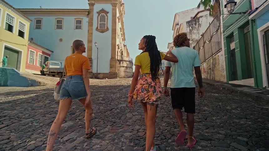 Three young people walking down a cobblestone street surrounded by classic colorful architecture