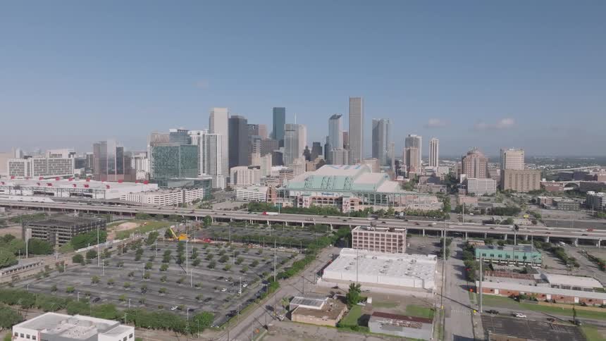 Aerial view of the downtown houston skyline featuring numerous skyscrapers urban infrastructure and a long stretch of busy overhead bridge at midday