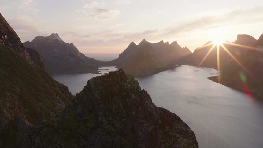 Ocean surrounded by mountains and sunrise on the horizon