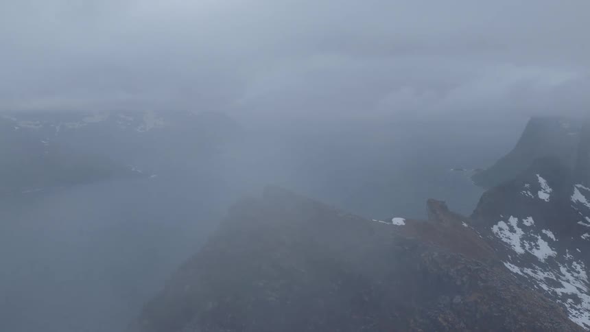 Aerial landscape of ocean surrounded by cliffy and snowy mountains